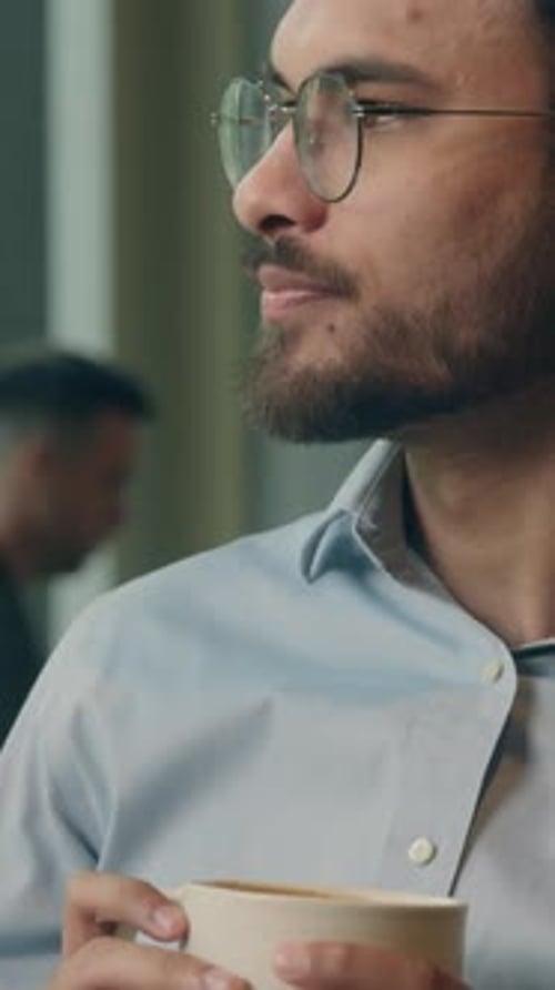 Man drinks coffee and smiles in bright setting