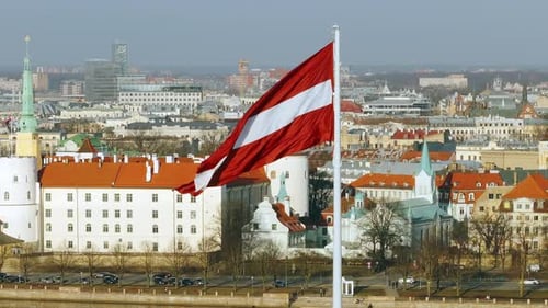 Latvian Flag Waving over Riga Cityscape