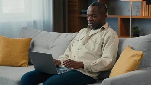 Man Sitting on Couch Working on Laptop