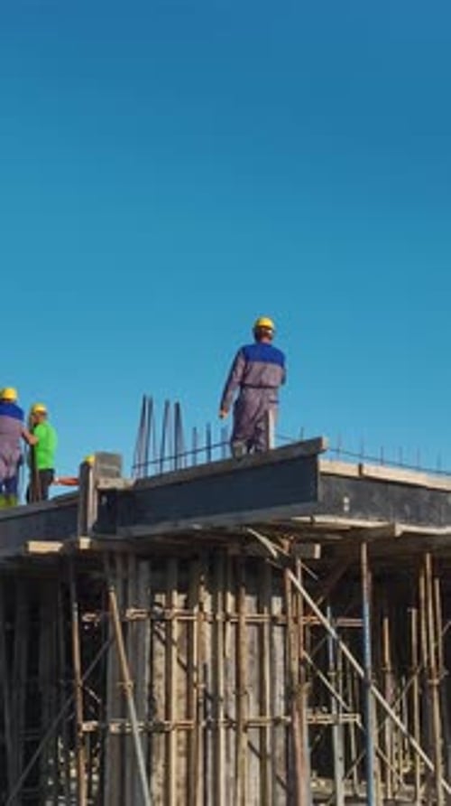 Vertical Video of Residential Construction With a Crane Lifting Materials and Workers Pouring