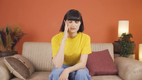 Pensive Woman Sitting Thoughtfully on Couch Indoors