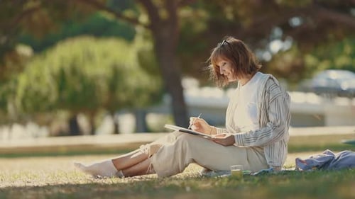 A Woman Sitting in the Park and Painting with Watercolors
