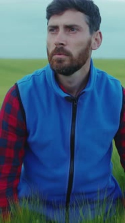 A Man in a Blue Vest Enjoys a Serene Green Field and Blue Sky