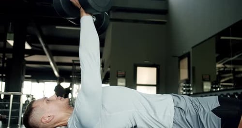 Young man bodybuilder has workout at gym and lifting dumbbells