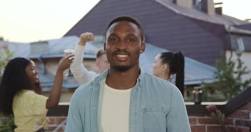 Smiling Man with Friends Celebrating on Rooftop