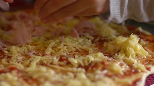 Adding ham onto a pizza before baking it