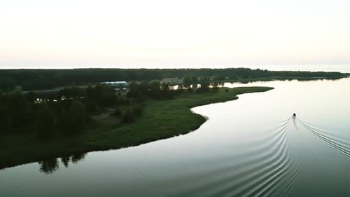 Tranquil View of a Serene River at Sunrise with a Peacefully Drifting Boat Captured From an Aerial