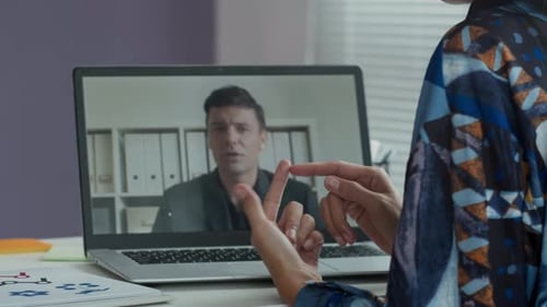 Businesswoman Talking to Male Colleague on Video Using Laptop at Office