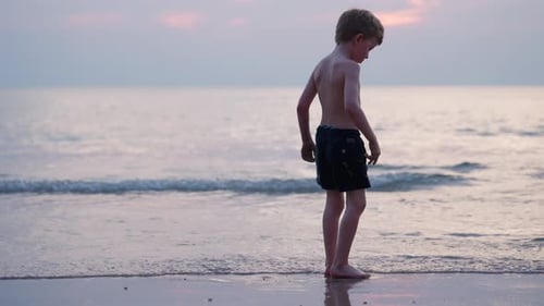 Boy on Beach at Sunset Walks Barefoot