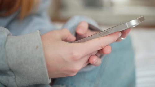 Side View Hand of Girl Using Smartphone in the Living Room at Home Typing Message