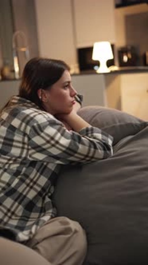 Thoughtful Woman Sitting on Couch at Night