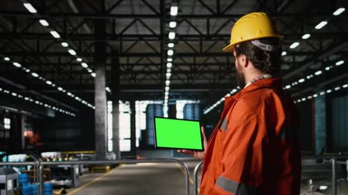 Isoliertes Modell auf einem Tablet, das von einem Ingenieur mit Helm in der Lagerhalle gehalten wird