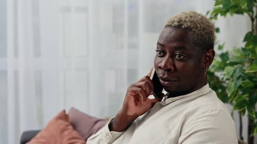 Man Talking on Cellphone While Sitting on Couch