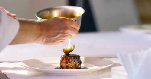 Chef Garnishing Gourmet Dish with Sauce