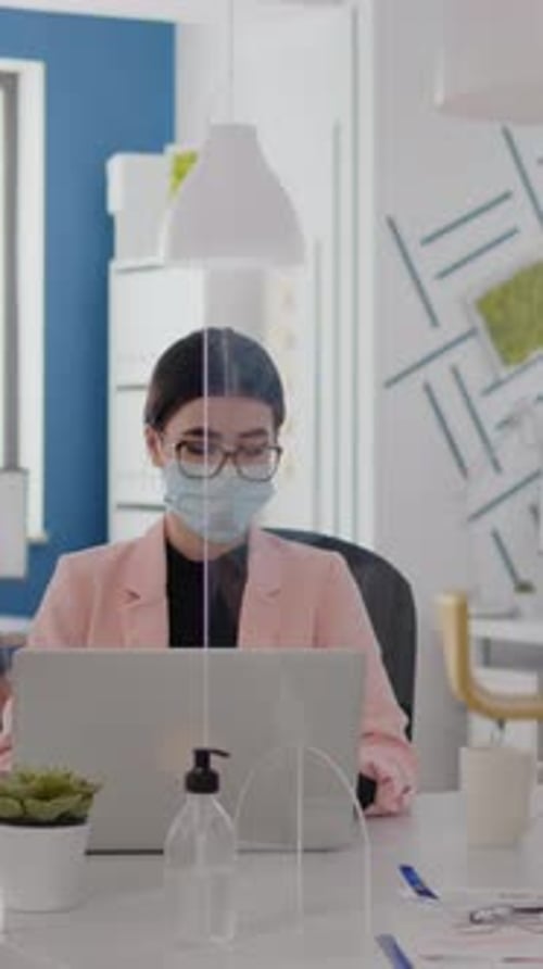 Woman Wearing Mask Works at Laptop in Office