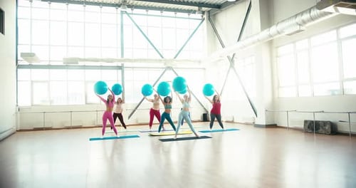 Frauen machen Fitnessübungen mit Fitball in Light Gym
