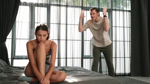 Angry Man Arguing with Upset Woman on Bed