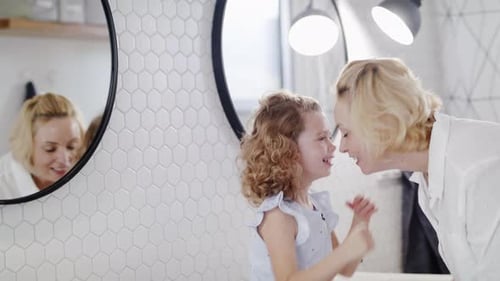 Blonde Woman and Young Girl Bonding in Bathroom