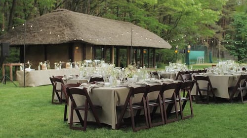 The Outdoor Wedding Decor is Beautifully Arranged with Tables in a Green Forest Glass Flowers