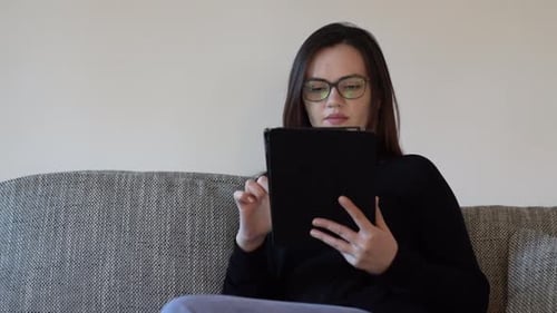 Woman Using Tablet at Home on Sofa