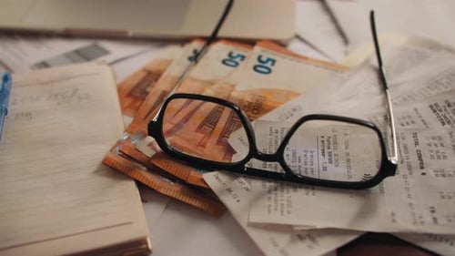 Close Up of Euro Bills, Glasses and Receipts
