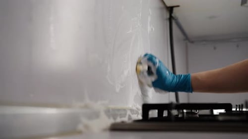Arm Cleans Kitchen Wall with Sponge and Soap