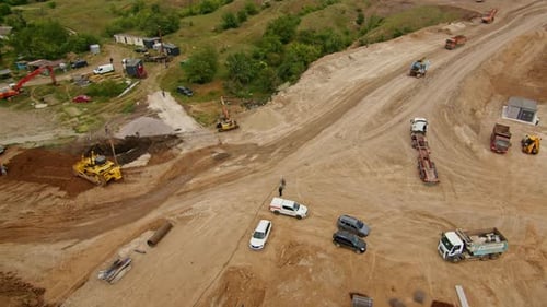 Aerial View of a Construction Site with Heavy Machinery Trucks and Workers Earthmoving and