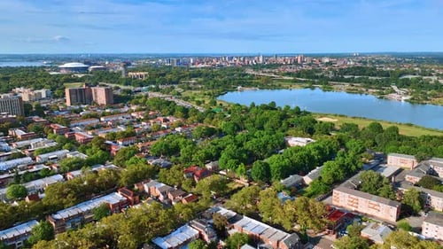 Es erhebt sich über dem grünen Viertel von New York mit einem großen Teich. Zahlreiche Autos rauschen auf der Autobahn vorbei.