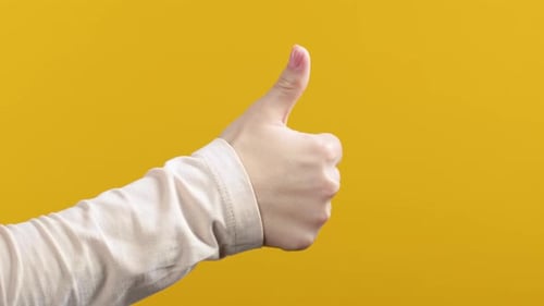 Hand Giving Thumbs Up on Yellow Background