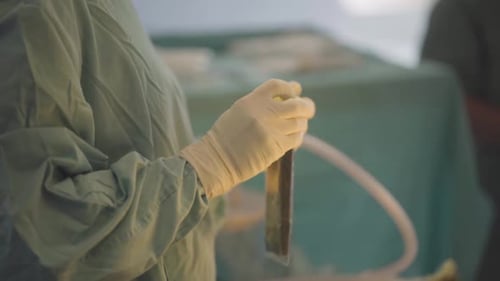 Nurse manipulating equipment used in an aesthetic surgery, showcasing precision and care in the medi