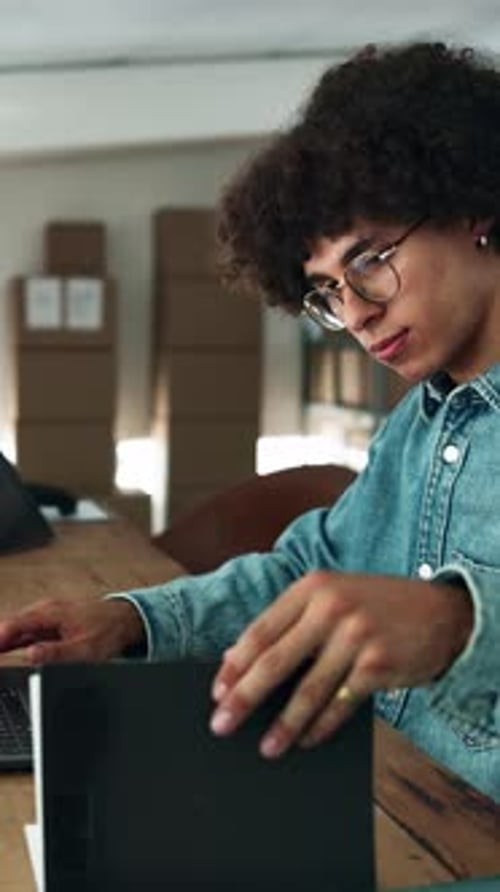 Book, laptop and logistics with man at desk in office for delivery or distribution schedule