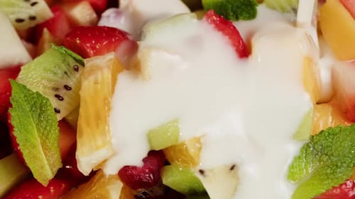 Pouring Yogurt on a Fresh Fruit Salad