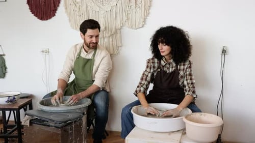 Man and Woman Potters Working on Potters Wheel in Studio