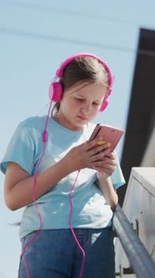Jeune fille porte un casque rose vif et tient un téléphone