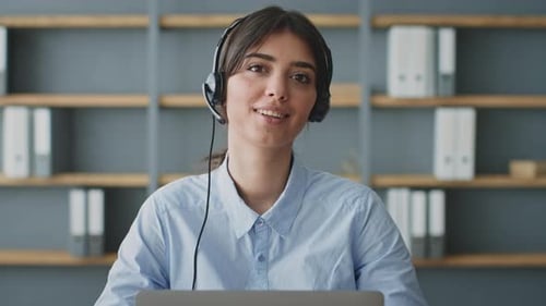 Smiling Woman Wearing Headset Sits at Desk