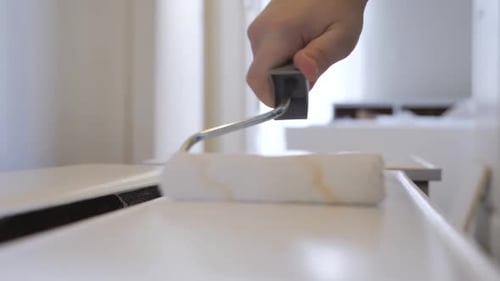 Paint Roller Applies White Paint to a Surface