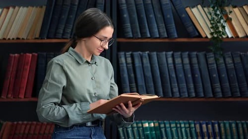 Nachdenkliche Studentin liest Papierbuch Auswahl von Literatur für Hausaufgaben an der Universitätsbibliothek