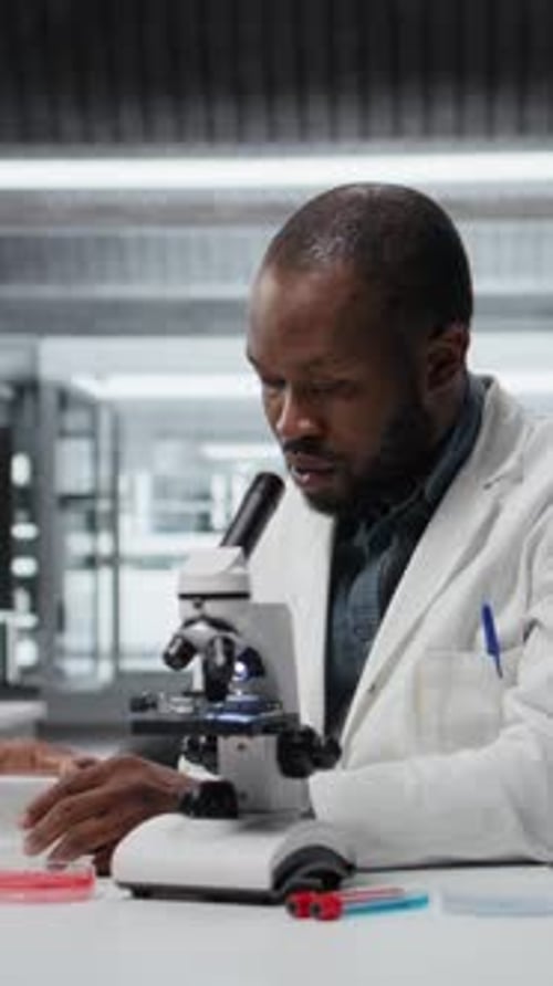 Male Scientist Analyzes Sample with Microscope in Lab