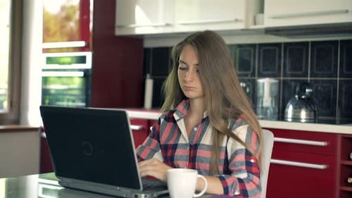 Young woman using laptop in kitchen at home