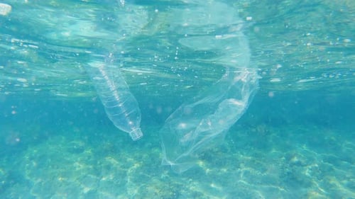 Plastic pollution in sea ocean, big environmental problem. Plastic bag and bottle floating in ocean.