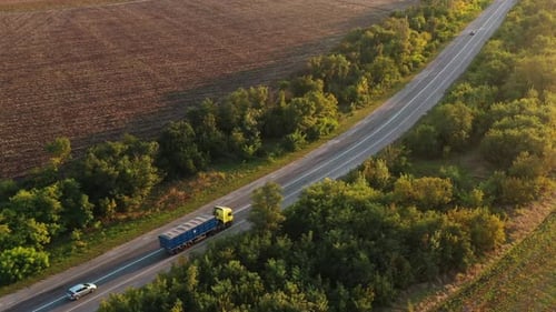 Aerial Shot of a Grain Truck Driving on the Road in Beautiful Countryside in the Summer Sunset Drone