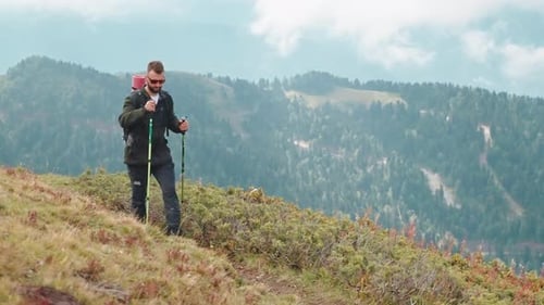 Explorer Hiker Man Hiking in Mountains Valley Holding Sticks in Hands