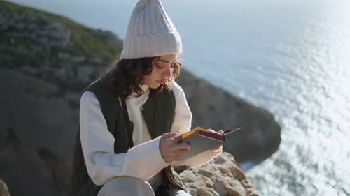 Chica tranquila disfrutando de un libro en Ocean Cliff Edge