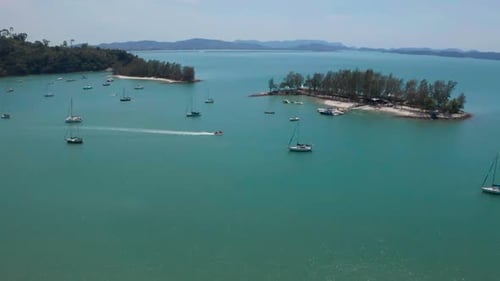 Luftaufnahmen eines Schnellboots zwischen Segelbooten im Meer. Türkisfarbenes Wasser in der kleinen Lagune L