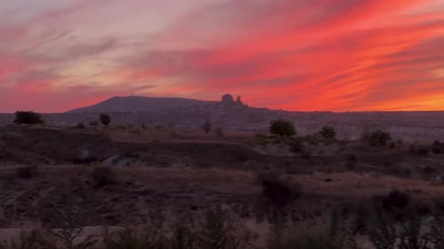 Red sky from the setting sun behind the distant mountain. View from a high mountain, with a canyon.
