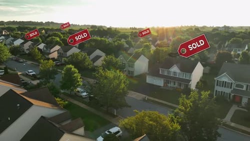 Aerial view of a suburban neighborhood at sunset with multiple "SOLD" signs above houses. Drone shot