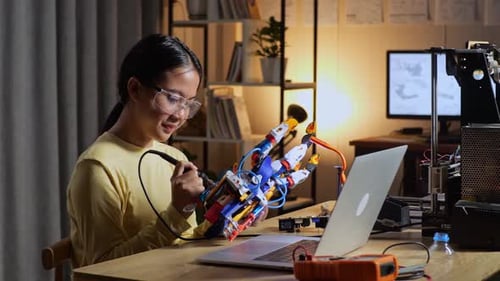 Young Adult Soldering Wires in a Robotic Hand