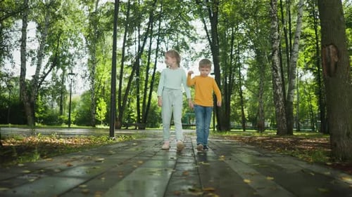 Siblings Walking Together on Leafy Path in City Park