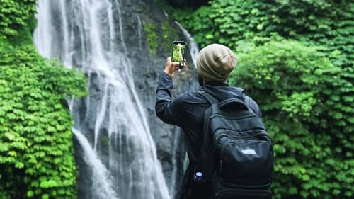 Traveling Man Making Phone Video of Green Forest and Mountain Waterfall Nature