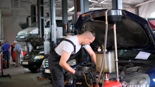 Mechanic Working on Motor Vehicle Engine in Garage